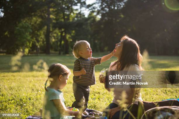 kid putting jelly in mother's mouth - picnic stock-fotos und bilder