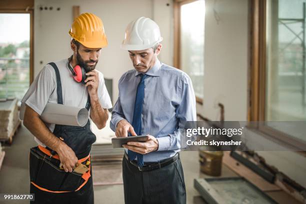 male foreman and manual worker using digital tablet at construction site. - foreman stock pictures, royalty-free photos & images