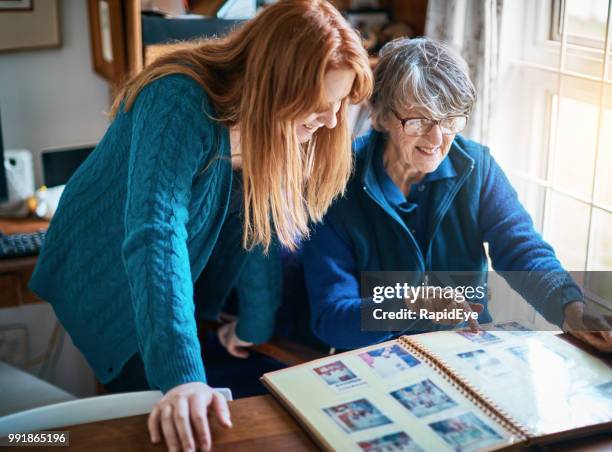 abuela y nieta feliz mirar a través de álbum familiar juntos - album de fotos fotografías e imágenes de stock