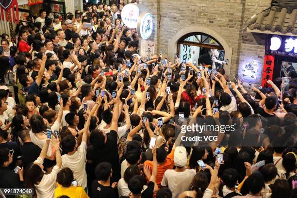 Fans record videos on their smartphones as boy band Modern Brothers performs during a live webcast at Andong Old Street on June 30, 2018 in Dandong,...
