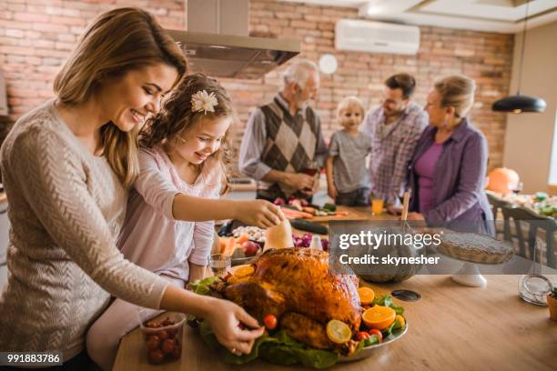 happy mother and daughter preparing roasted turkey for thanksgiving dinner. - mom preparing food stock pictures, royalty-free photos & images