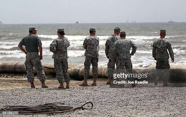 Louisiana National guard members stand near the area where what appears to be small oil globs have washed ashore at Fourchon Beach as efforts...