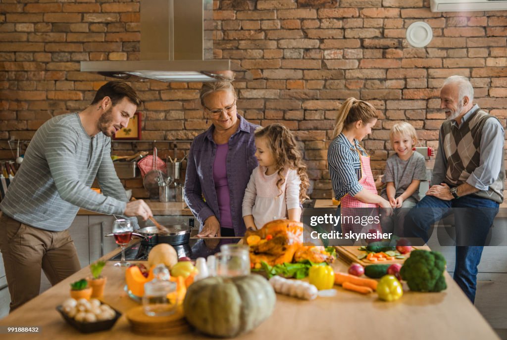 Happy multi-generation family preparing Thanksgiving dinner in the kitchen.