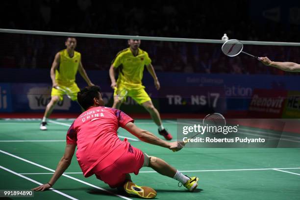 Wang Yilyu of China falls as he compete against Liu Cheng and Zhang Nan of China during the Men's Doubles Round 2 match on day three of the Blibli...