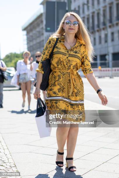 Guest is seen attending Rebekka Ruetz wearing a yellow with black design dress and black shoulder bag during the Berlin Fashion Week July 2018 on...