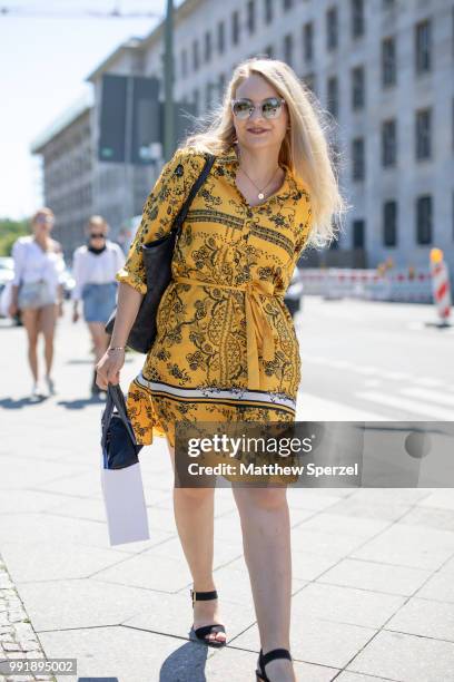 Guest is seen attending Rebekka Ruetz wearing a yellow with black design dress and black shoulder bag during the Berlin Fashion Week July 2018 on...