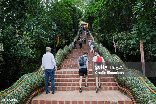 Tourists walk up a flight of stairs to Wat Phra That Doi Suthep in Chiang Mai, Thailand, on Wednesday, July 4, 2018. Thai inflation...