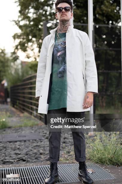 Guest is seen attending Danny Reinke wearing a white coat with green dog print shirt during the Berlin Fashion Week July 2018 on July 4, 2018 in...