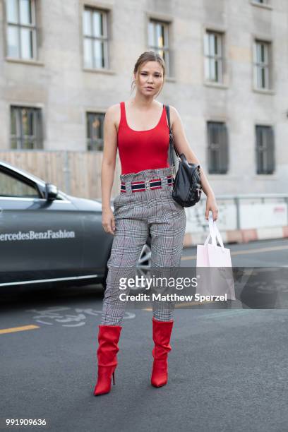 Guest is seen attending Riani wearing a red bodysuit with grey high-waisted pants, red shoes and belt during the Berlin Fashion Week July 2018 on...