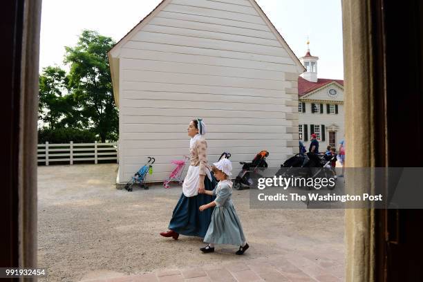 Malinda Billings and her daughter, Adelaide Billings walks past strollers as people gather to celebrate the Fourth of July at George Washington's...