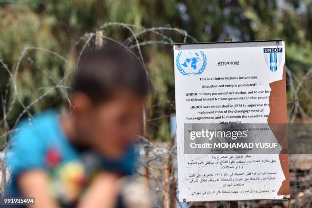 Displaced Syrian child from the province of Daraa sits near a UNDOF sign at a UN base on the border between Syria and the Israeli-occupied Golan...