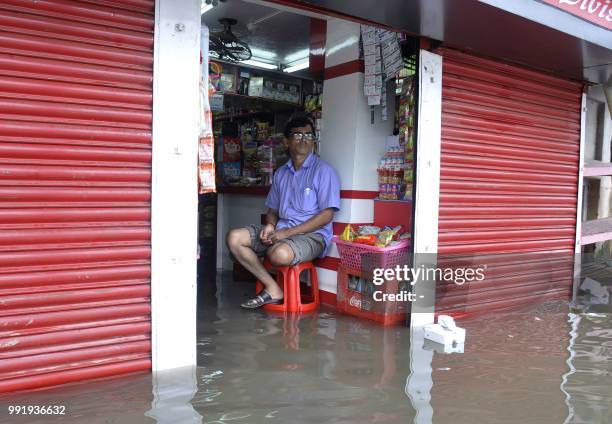 Shopkeeper sits inside his flooded shop after heavy rain in Agartala in India's northeast Tripura state on July 5, 2018.