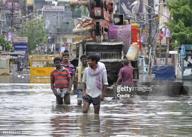 People wade along a flooded street after heavy rain in Agartala in India's northeast Tripura state on July 5, 2018.