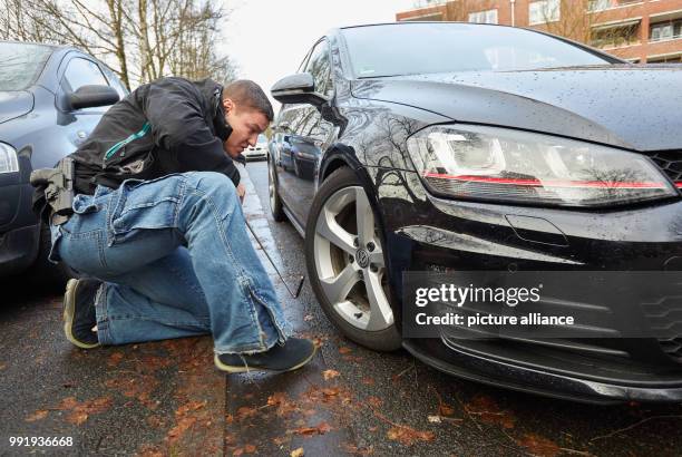 Police Chief Commissioner Sebastian Bauch from the control group "Autoposer" inspects a Golf GTI with a mirror in Hamburg, Germany, 19 November 2017....