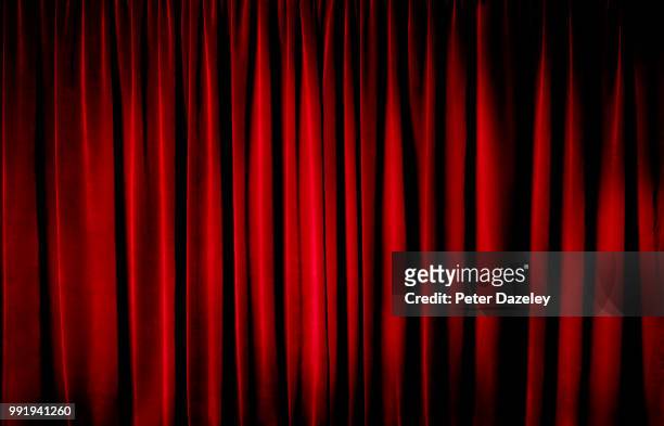 darkly lit theatre curtains - rosso foto e immagini stock