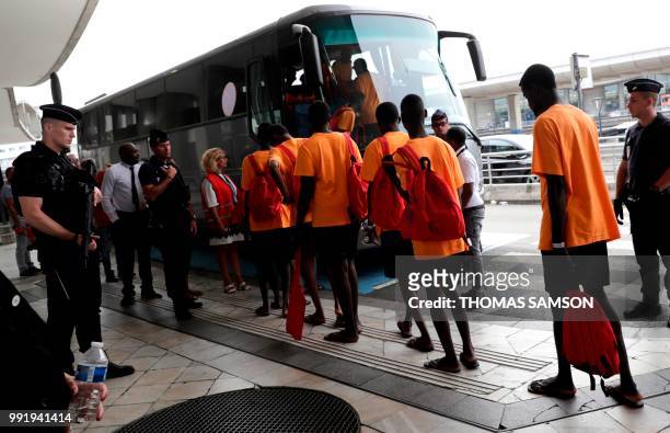 Some of the 50 migrants board a waiting bus as they leave the immigration hall at Roissy-Charles de Gaulle airport on the outskirts of Paris on July...