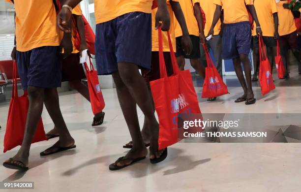 Some of the 50 migrants holds bags given to them by the OFII as they gather in the immigration hall at Roissy-Charles de Gaulle airport on the...