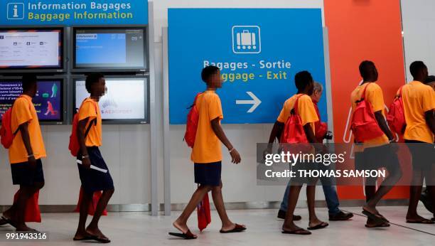 Some of the 50 migrants carrying bags given to them by the OFII leave the immigration hall at Roissy-Charles de Gaulle airport on the outskirts of...