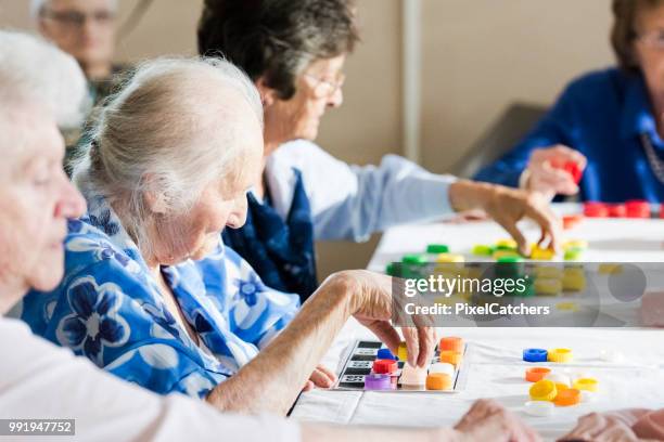 senior femenino juegan varios cartones de bingo - game night leisure activity fotografías e imágenes de stock