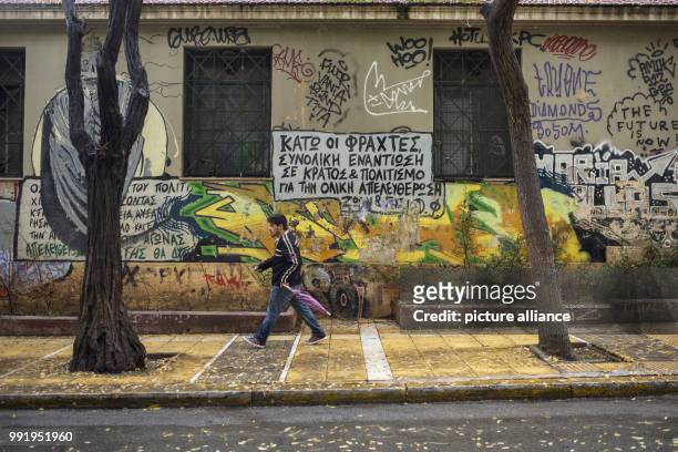 Man walks past a house that is covered with graffitis in the Exarchia quarter in Athens, Greece, 19 November 2017. The lettering 'total resistance...