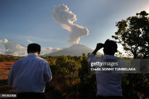 People stop to watch as Mount Agung volcano sends up another plume of smoke, seen from the Kubu subdistrict in Karangasem Regency on Indonesia's...