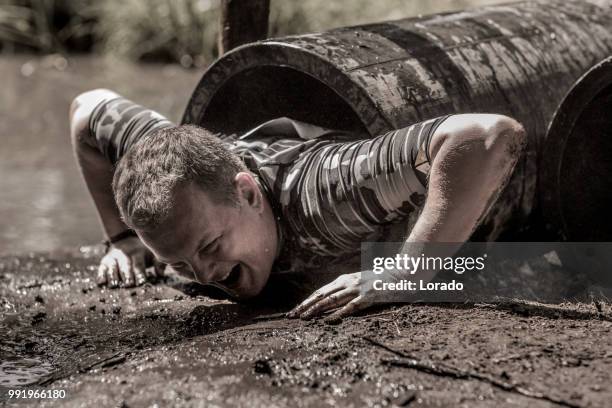 einzelne mensch sportlichen spaß an einem öffentlichen schlamm laufen hindernis-parcours - assault courses stock-fotos und bilder