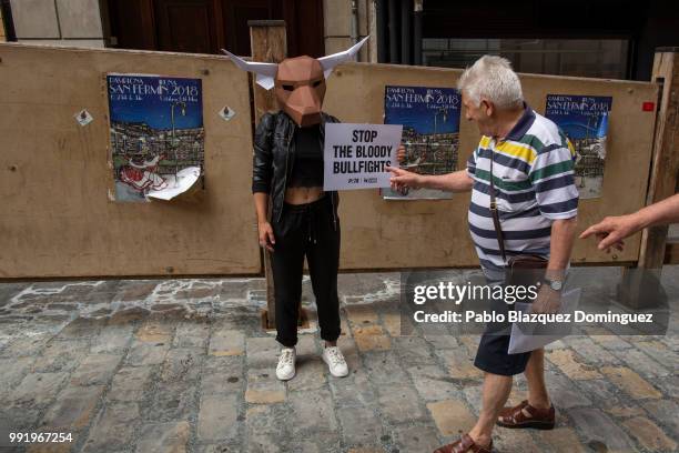 An animal rights activist holds a placard reading 'Stop the bloody bullfights' as two men ask what does it mean after a protest against bullfights...