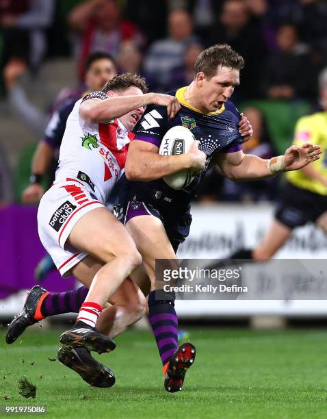 Ryan Hoffman of the Storm is is tackled by Dragons defense as he scores a try during the round 17 NRL match between the Melbourne Storm and the St...