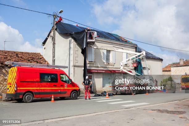 Workers repair the roof of a bakery in the village of Saint-Sornin on July 5 after violent hailstorms ripped through the area some 80kms north-west...