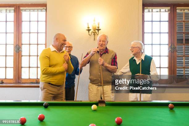 pensionierte senioren freunde, die austausch von lacht - snookerkugel stock-fotos und bilder