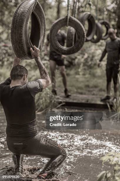 individual man having sporty fun at a public mud run obstacle course - military training stock pictures, royalty-free photos & images