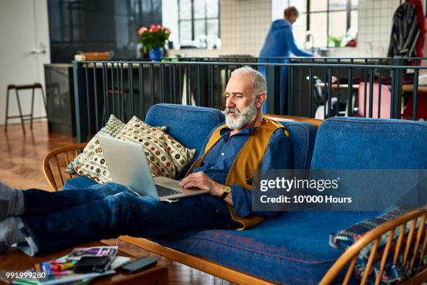 senior man with trendy moustache working on laptop at home - handlebar moustache stock pictures, royalty-free photos & images
