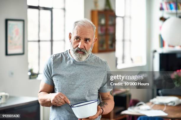 portrait of senior man holding bowl and preparing food - beard stockfoto's en -beelden