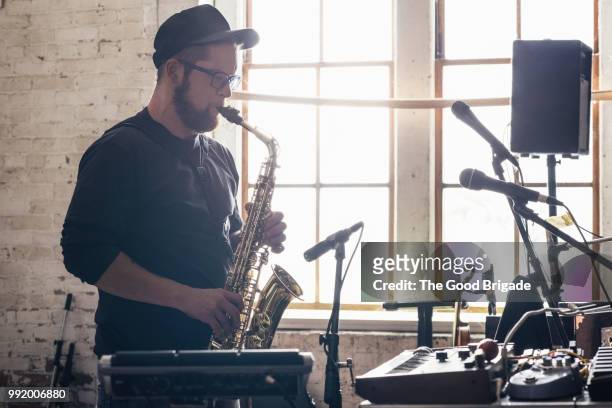 young man playing saxophone in recording studio - saxophone player stock pictures, royalty-free photos & images