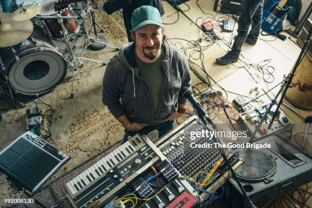 confident mid adult musician standing with musical instruments - portrait im raum stock-fotos und bilder