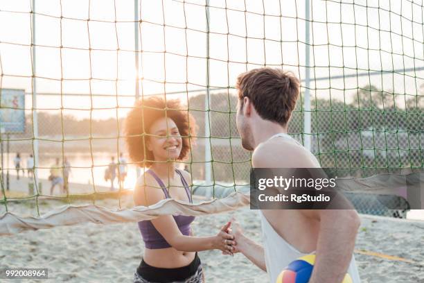 athletic couple shaking hands after beach volleyball - beach volleyball team stock pictures, royalty-free photos & images