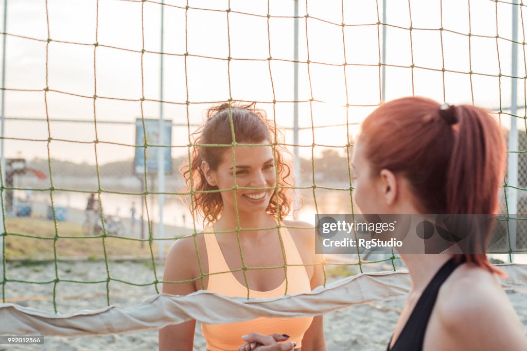 女性の若い選手がビーチバレーの試合後に握手