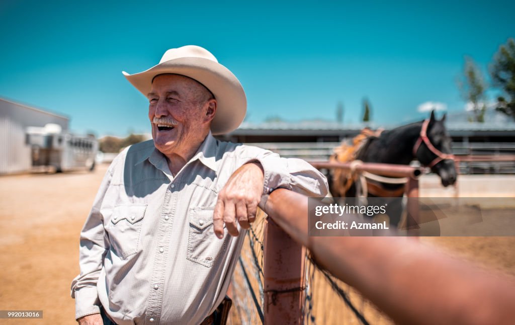 Cowboy leaning on a fence and holding lasso in rodeo arena