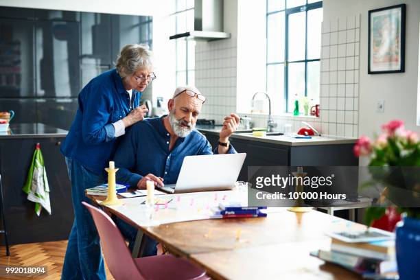 senior couple planing vacation with map and laptop on table - pensionamento foto e immagini stock