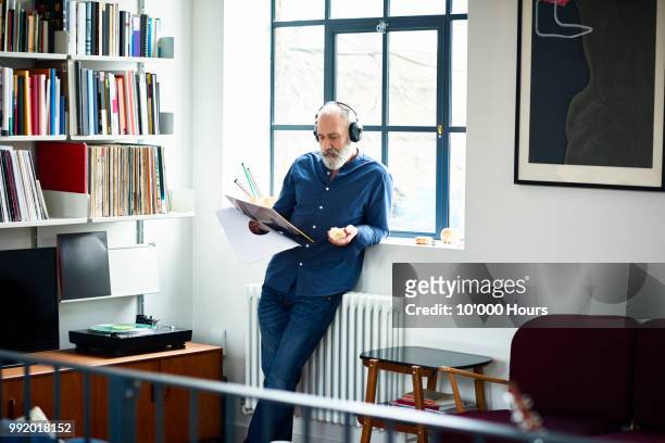 cool looking senior man in apartment listening to vinyl record - one man only photos 個照片及圖片檔