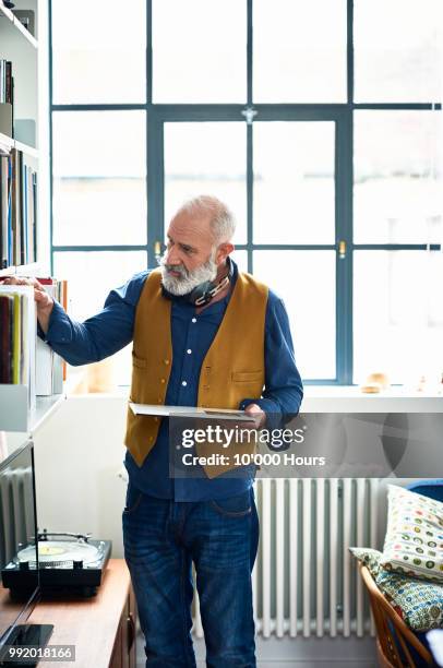 hipster senior man choosing record from collection on shelf - portrait choice stockfoto's en -beelden