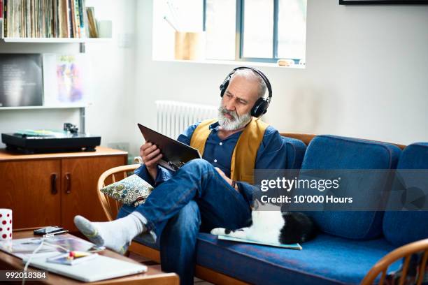 hipster man wearing headphones listening to record and reading cover - comfortable retirement stock pictures, royalty-free photos & images