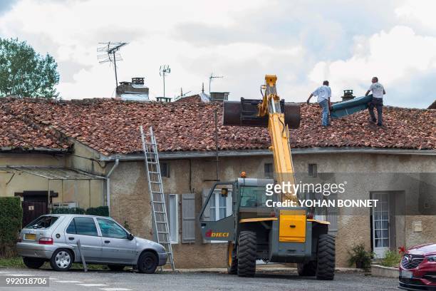 Workers repair the roof of a building in the village of Saint-Sornin on July 5 after violent hailstorms ripped through the area some 80kms north-west...