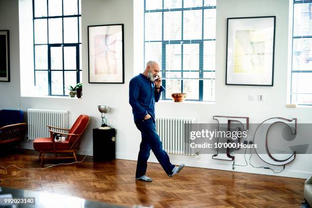 hipster senior man on cell phone in funky apartment - cool senior using cell phone foto e immagini stock