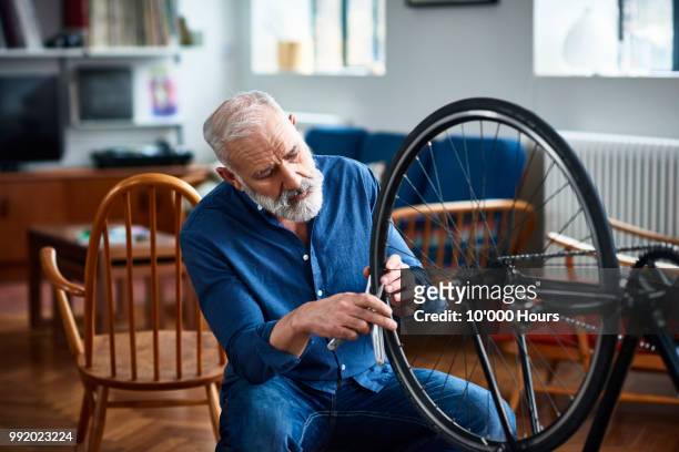 senior man removing bicycle tyer to repair a puncture - men hobbies stock pictures, royalty-free photos & images