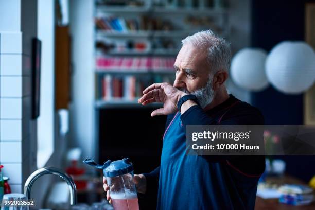senior man with grey hair wiping mouth and drinking health shake - mano tapando la boca fotografías e imágenes de stock