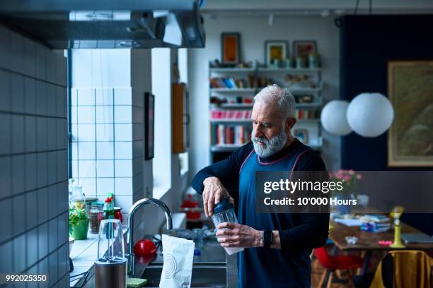 senior man making protein shake before exercising - molke stock-fotos und bilder