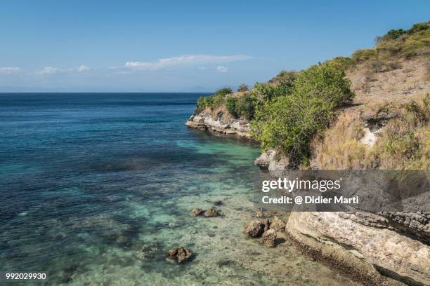 stunning rugged coast of south lombok with the sumbawa island in the distance in indonesia - didier marti stock pictures, royalty-free photos & images