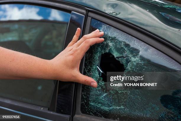 Resident's hand shows the damage to a window of vehicle in the village of Saint-Sornin on July 5 after violent hailstorms ripped through the area...