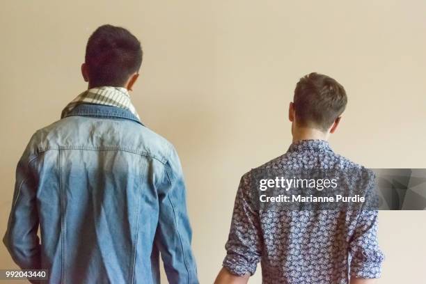 two men holding hands, facing the wall - androgynous 個照片及圖片檔